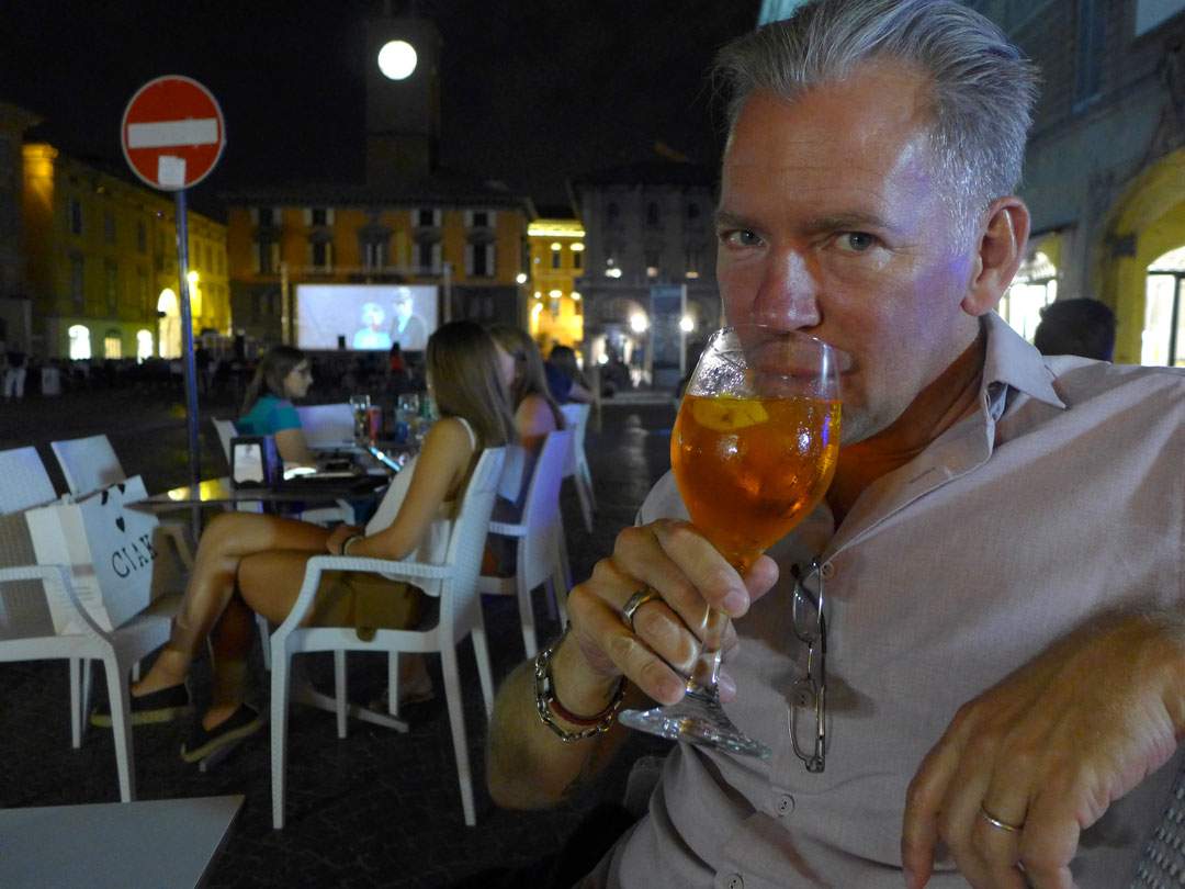 Erik drikker Spritz med utekinoen i bakgrunnen.