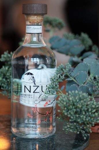 Jinzu Gin er utsmykket nydelig med japanske kirsebærblomster og et lite fuglebur på baksiden der fuglen, som sitter på front, har rømt fra.